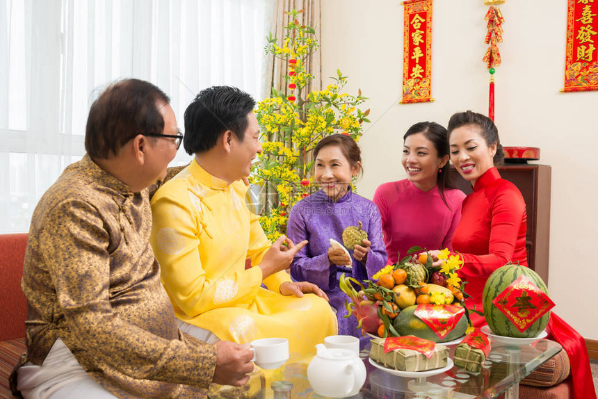 亚洲幸福家庭在家里庆祝新年节时享受新鲜水果与对来年背景最良好祝愿的一对相图片