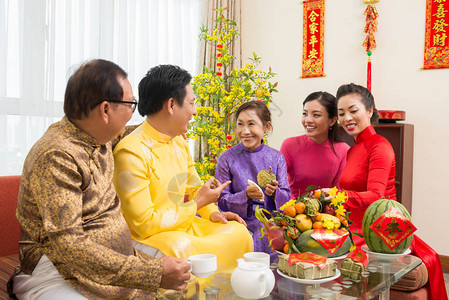 亚洲幸福家庭在家里庆祝新年节时享受新鲜水果与对来年背景最良好祝愿的一对相图片