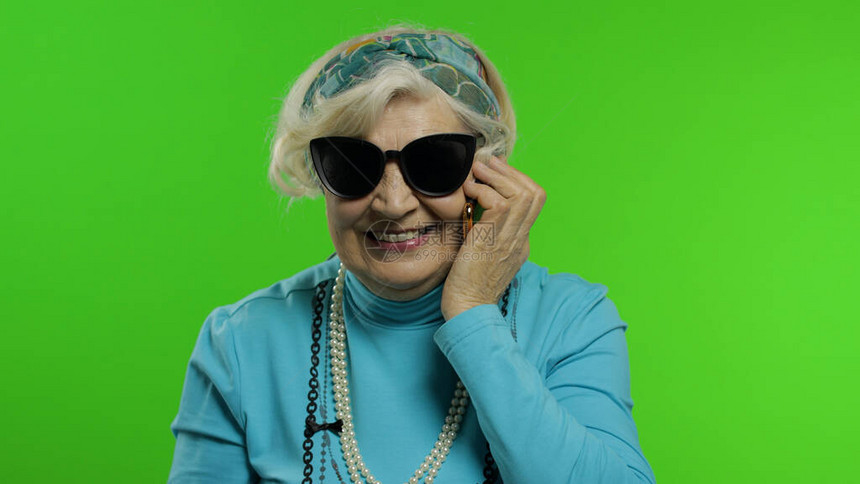 老年时尚奶白种人成熟女人在手机上情绪化地交谈色度键背景时尚的老奶在退休年龄穿着时尚服装图片