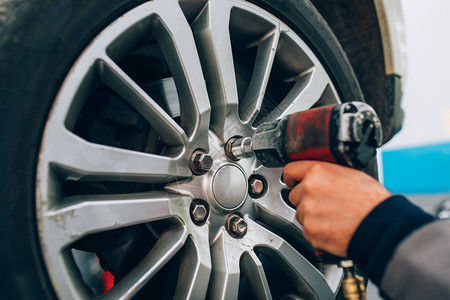 机械师在汽车修理店更换车轮修理汽车库用手和工具调整轮图片