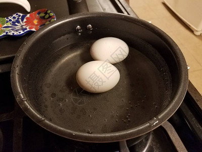 两个鸡蛋在炉子上的一壶水中煮沸图片