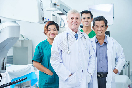 在医院手术室站立的多族裔医生和外科医生中微笑图片