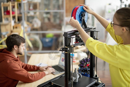 年轻女办公室女职员在3D打印机上用红丝换水池图片