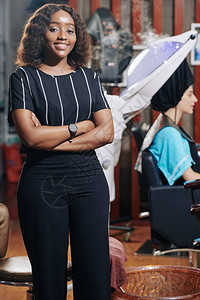快乐的康菲登尔理发师肖像站在她的手臂上站立折叠当客户坐在背景的图片