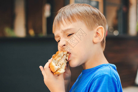 饥饿的孩子在户外咖啡馆吃汉堡可爱的孩子吃快餐童年图片