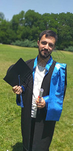 青年研究生在草地上拥有文凭和毕业证书垂直照片图片
