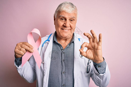 戴听诊器的老帅医生拿着粉红癌丝带图片