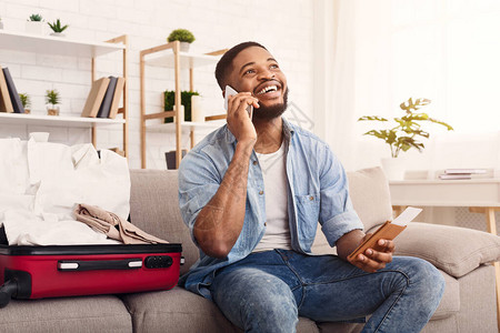 快乐的黑人男子在家中用手提箱坐着图片