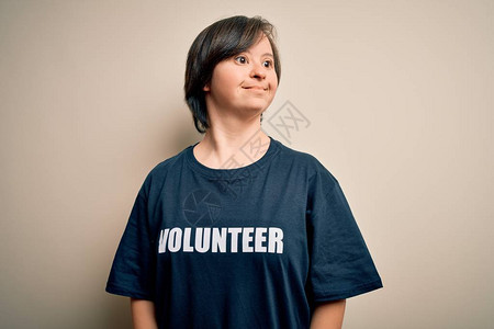 身穿社会护理慈善T恤的年轻综合症志愿者妇女微笑地向一边看图片