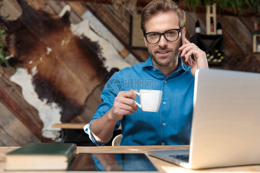 戴着眼镜的商人坐在办公桌前喝咖啡图片