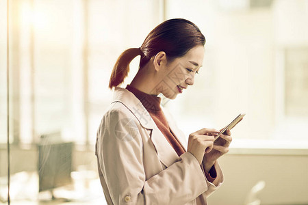 年轻的亚洲女企业家使用手机查看或发送短信图片