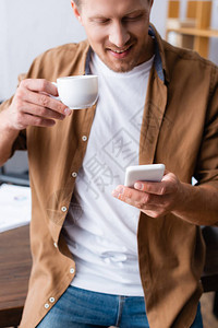 商人穿便衣手持咖啡在智能手机上聊天图片