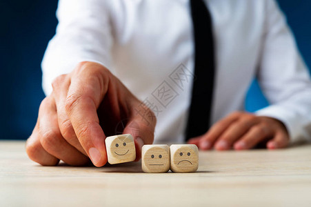 在顾客满意度的概念形象中以微笑的面容选择木骰子的人被紧贴图片