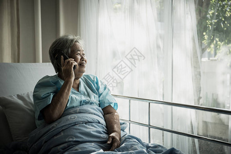 女病人在医院躺在床上时通过电话交谈图片