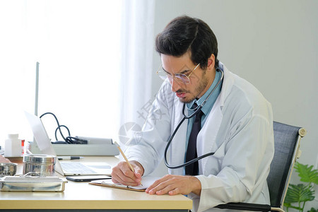医生正在医院桌上记录病人治疗的症状和细节请查看InfoFin图片
