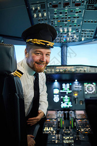 快乐自信留着胡子的英俊机长戴着帽子坐在副驾驶座位上图片