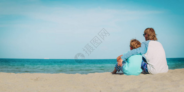 父亲和小儿子在海滩度假时抱图片
