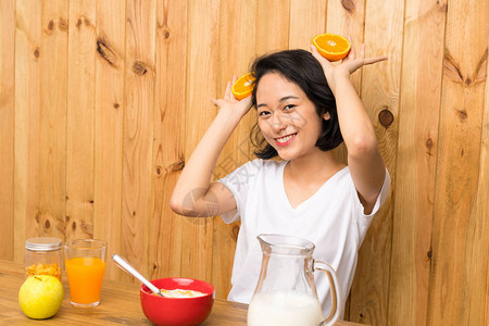 亚洲年轻女子拿着橘子吃早餐图片