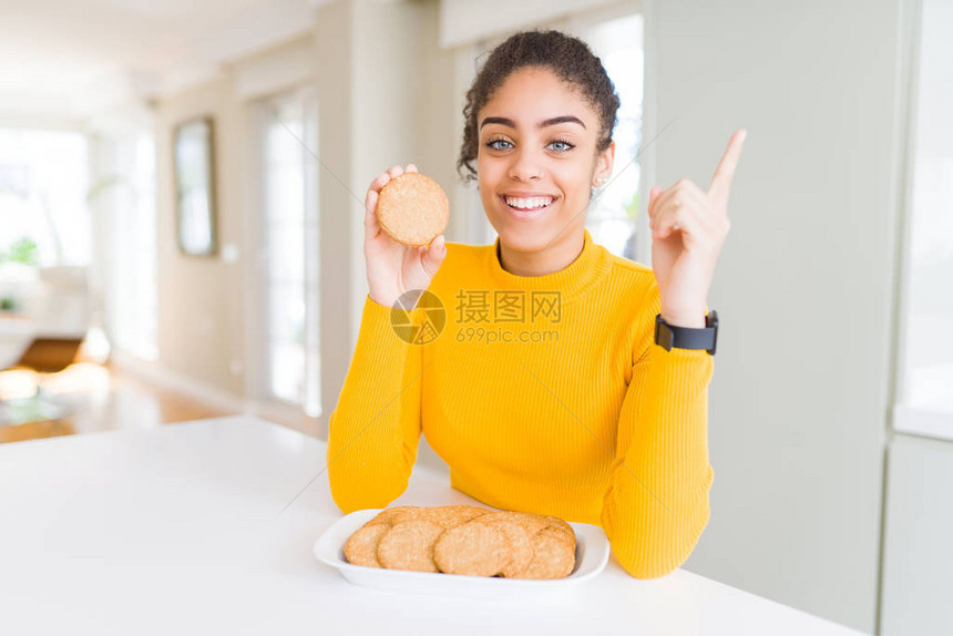吃健康全麦饼干的非洲裔美国小女孩非常高兴地用手和图片