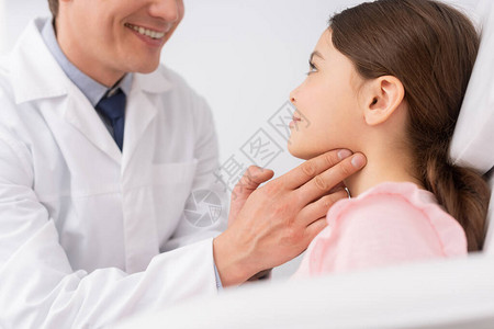 在检查可爱孩子的喉咙时抚摸其颈部的笑着随从医生切动图片