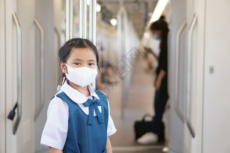 亚洲儿童学生或小女孩微笑在天空列车或电动火车上戴面罩图片