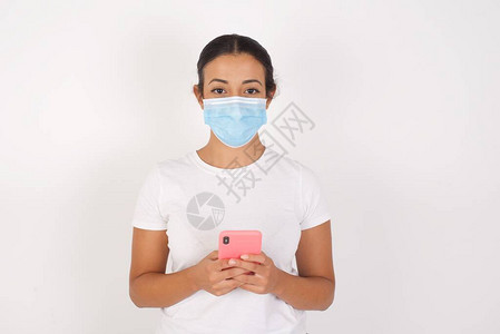 年轻的阿拉伯妇女戴着医用口罩站在孤立的白色背景上图片
