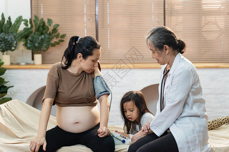 亚洲高级女医生家访年轻孕妇患者图片