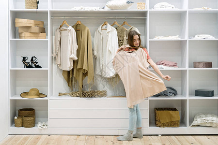 年轻的成年女站在家里的现代衣柜附近图片