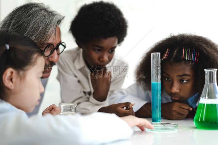 一群青少年学生在学校桌上的实验室课堂上学习和做化学实验并手持试图片