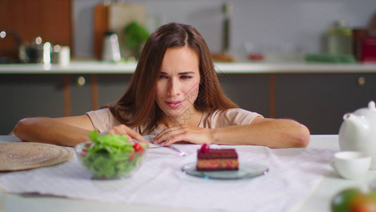 快乐的女人在慢动作中看着厨房里的蛋糕和新鲜沙拉的特写镜头图片
