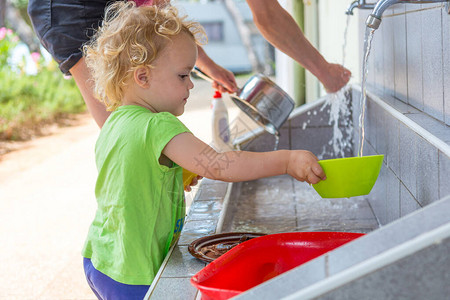 小女孩在户外帮忙洗碗学习做家务图片