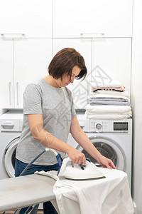 妇女用洗衣机在洗衣房洗衣服的衣图片