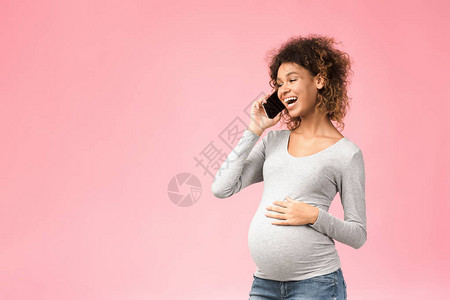 快乐的黑人孕妇与医生通过电话咨询粉红背图片
