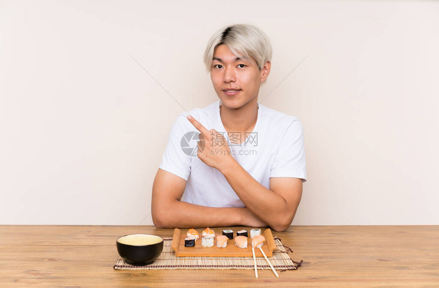 年青的亚洲男人在桌子上吃寿司图片