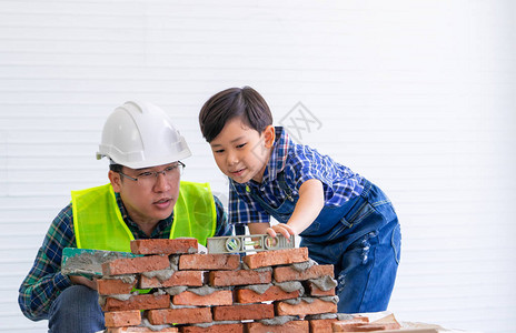 小男孩正在学习如何从建筑工父亲那里图片