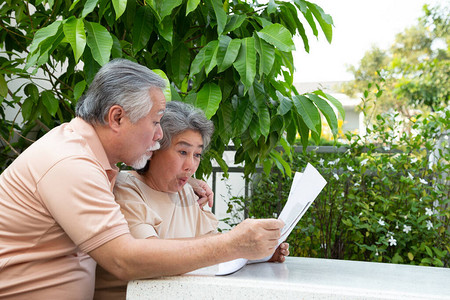 兴奋的亚洲老夫妇在前花园的家中阅读报纸或杂志时图片