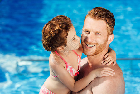 快乐的父亲和女儿拥抱在游泳池里图片
