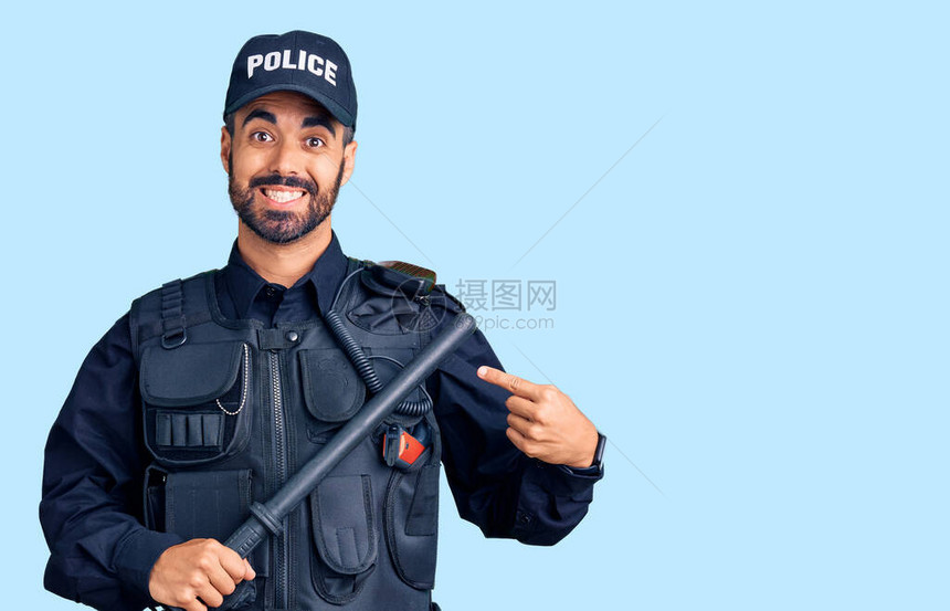 身穿警服的西班牙裔年轻男子手持警棍微笑着用手和指高图片