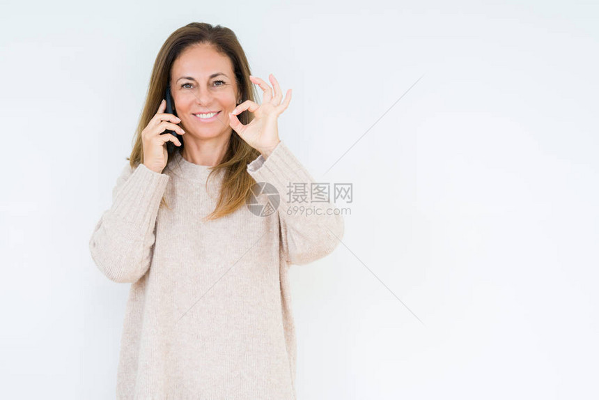 中年女在孤立的背景里用智能手机说话图片