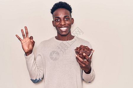 带着巧克力麦片的年轻非洲男子用手指做好标记笑着亲爱地摆弄优秀的象图片