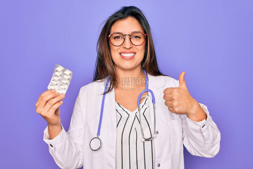 紫色背景中拿着药丸的年轻职业医生女开心地笑着做好手势图片