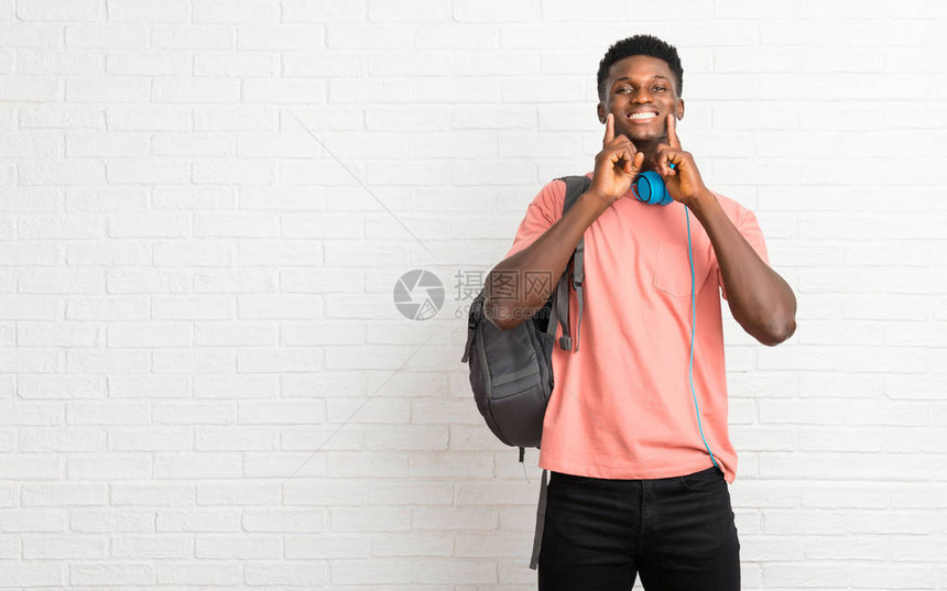 年轻的美国黑人男学生用手指着嘴和脸图片