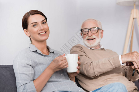 快乐的女子与茶水看着镜头坐在父亲身图片