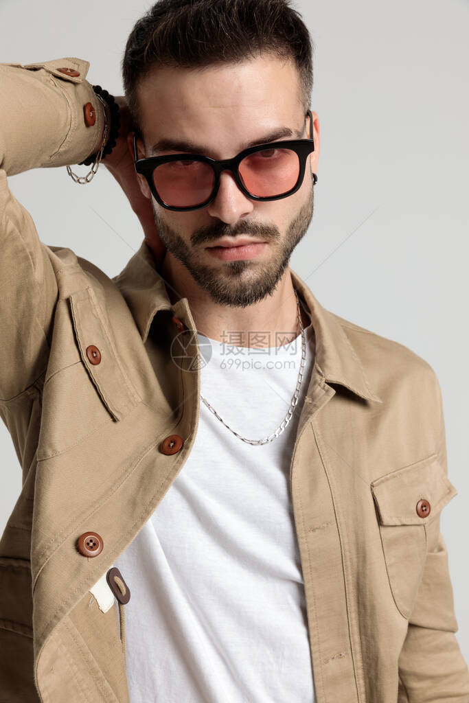 穿着夹克戴着墨镜手放在脖子后面的帅气未刮胡子的年轻人图片