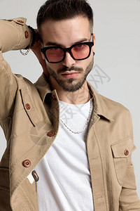 穿着夹克戴着墨镜手放在脖子后面的帅气未刮胡子的年轻人图片