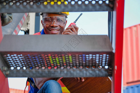 非洲技术员带着对讲机透过大卡车在货集装箱运输区图片