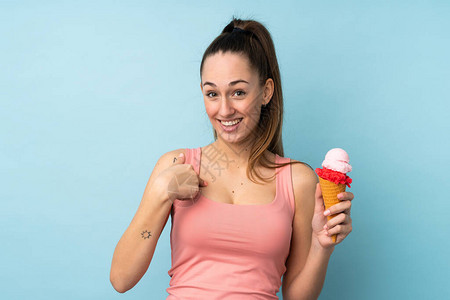 青红色的年轻黑发女人一个玉米角冰淇淋在孤立的蓝背景上面部图片