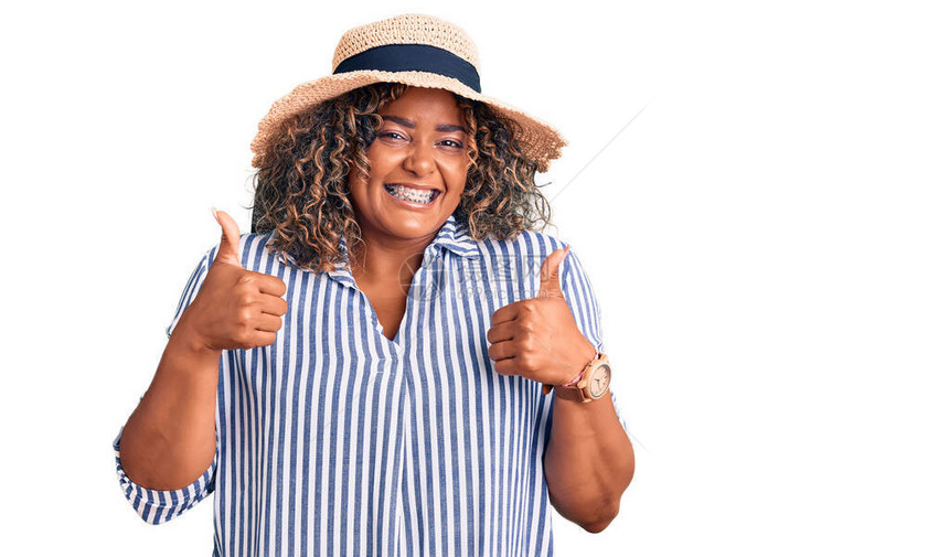 身着夏帽成功标志的年轻非裔美国人加体型女用手大拇指微笑和快乐地做积极姿态欢乐的表情和图片