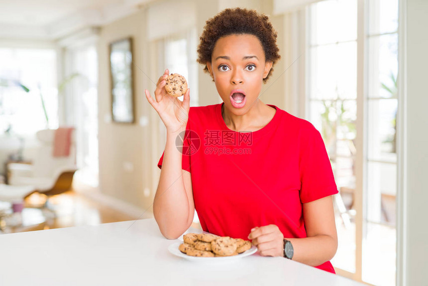 吃巧克力饼干的年轻非洲裔美国女惊恐地吓得满脸吃惊图片
