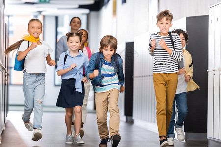 兴奋的多元文化学生在学校走廊上奔跑图片